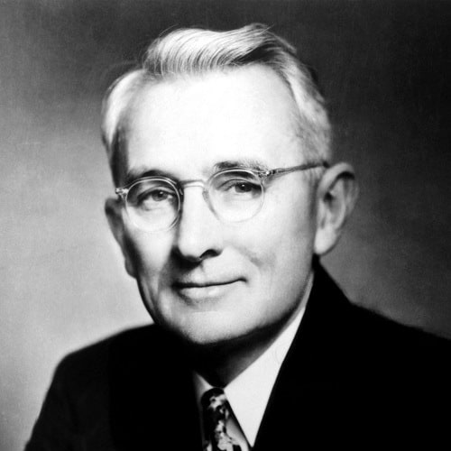 Black and white portrait of an elderly man with glasses, wearing a suit and a patterned tie, smiling gently at the camera, reminiscent of the timeless wisdom in "How To Win Friends And Influence People